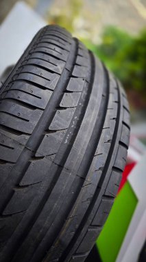 Gıcır gıcır yeni bir araba lastiğinin detaylı görüntüsü. Gelişmiş tutuş ve performans için karmaşık lastik kalıplarını gösteriyor.