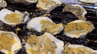 Istakoz ızgaralarını meşale kullanarak açık ateşin üzerinde pişiriyor, hareketli bir sokak yemeğinin canlı atmosferini yakıyor. Parlak alevler ve yeni hazırlanmış deniz ürünleri ile Tayland marketi..