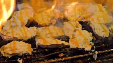 Istakoz ızgaralarını meşale kullanarak açık ateşin üzerinde pişiriyor, hareketli bir sokak yemeğinin canlı atmosferini yakıyor. Parlak alevler ve yeni hazırlanmış deniz ürünleri ile Tayland marketi..