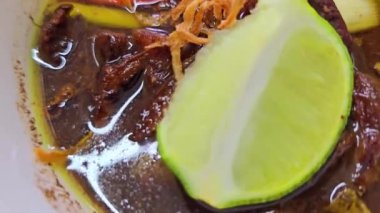 Rawon çorbası ya da Endonezya siyah et çorbası, siyah renk Endonezya fındığı Kluwek 'ten. Limon, biber ezmesi, tuzlu yumurta ve krakerle servis edilir. Yemek tarifi, makale veya herhangi bir yemek içeriği veya blog için mükemmel
