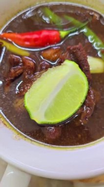 Rawon çorbası ya da Endonezya siyah et çorbası, siyah renk Endonezya fındığı Kluwek 'ten. Limon, biber ezmesi, tuzlu yumurta ve krakerle servis edilir. Yemek tarifi, makale veya herhangi bir yemek içeriği veya blog için mükemmel