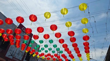 Canlı kırmızı ve sarı fenerler, Çin 'in yeni yılını ve geleneksel kültür dekoru kutlamalarını temsil eden huzurlu mavi gökyüzünün altında açık balkonlarda asılı duruyor. arkaplan için iyi