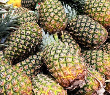 Tropikal bir atmosfer sergileyen taze, olgun ananasların renkli bir görüntüsü. Parlak ve detaylı görüntü meyvelerin sulandırıcılığını ve doğal çekiciliğini vurgular..