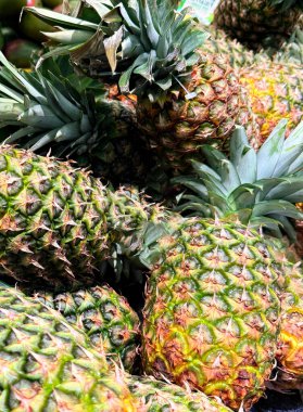 Tropikal bir atmosfer sergileyen taze, olgun ananasların renkli bir görüntüsü. Parlak ve detaylı görüntü meyvelerin sulandırıcılığını ve doğal çekiciliğini vurgular..