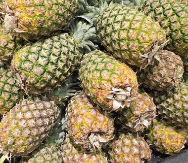 Tropikal bir atmosfer sergileyen taze, olgun ananasların renkli bir görüntüsü. Parlak ve detaylı görüntü meyvelerin sulandırıcılığını ve doğal çekiciliğini vurgular..