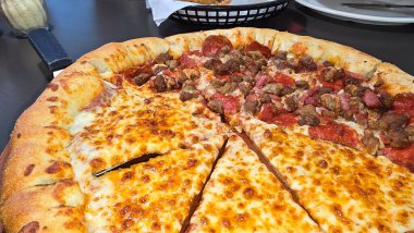Tahta bir tahtanın üzerinde servis edilen peynirle et severlerin karışımından oluşan lezzetli bir pizza. Doldurulmuş altın peynir ve erimiş peynir taze ve karşı konulmaz lezzetleri vurgular ve ağız sulandırıcı bir mutfak deneyimi yaratır..