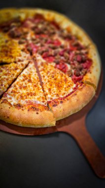 Tahta bir tahtanın üzerinde servis edilen peynirle et severlerin karışımından oluşan lezzetli bir pizza. Doldurulmuş altın peynir ve erimiş peynir taze ve karşı konulmaz lezzetleri vurgular ve ağız sulandırıcı bir mutfak deneyimi yaratır..