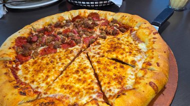 Tahta bir tahtanın üzerinde servis edilen peynirle et severlerin karışımından oluşan lezzetli bir pizza. Doldurulmuş altın peynir ve erimiş peynir taze ve karşı konulmaz lezzetleri vurgular ve ağız sulandırıcı bir mutfak deneyimi yaratır..