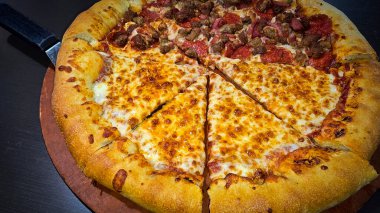 Tahta bir tahtanın üzerinde servis edilen peynirle et severlerin karışımından oluşan lezzetli bir pizza. Doldurulmuş altın peynir ve erimiş peynir taze ve karşı konulmaz lezzetleri vurgular ve ağız sulandırıcı bir mutfak deneyimi yaratır..