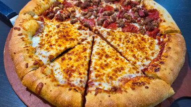 Tahta bir tahtanın üzerinde servis edilen peynirle et severlerin karışımından oluşan lezzetli bir pizza. Doldurulmuş altın peynir ve erimiş peynir taze ve karşı konulmaz lezzetleri vurgular ve ağız sulandırıcı bir mutfak deneyimi yaratır..