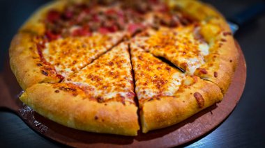 Tahta bir tahtanın üzerinde servis edilen peynirle et severlerin karışımından oluşan lezzetli bir pizza. Doldurulmuş altın peynir ve erimiş peynir taze ve karşı konulmaz lezzetleri vurgular ve ağız sulandırıcı bir mutfak deneyimi yaratır..