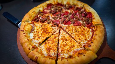 Tahta bir tahtanın üzerinde servis edilen peynirle et severlerin karışımından oluşan lezzetli bir pizza. Doldurulmuş altın peynir ve erimiş peynir taze ve karşı konulmaz lezzetleri vurgular ve ağız sulandırıcı bir mutfak deneyimi yaratır..