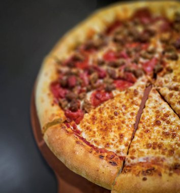 Tahta bir tahtanın üzerinde servis edilen peynirle et severlerin karışımından oluşan lezzetli bir pizza. Doldurulmuş altın peynir ve erimiş peynir taze ve karşı konulmaz lezzetleri vurgular ve ağız sulandırıcı bir mutfak deneyimi yaratır..