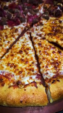 Tahta bir tahtanın üzerinde servis edilen peynirle et severlerin karışımından oluşan lezzetli bir pizza. Doldurulmuş altın peynir ve erimiş peynir taze ve karşı konulmaz lezzetleri vurgular ve ağız sulandırıcı bir mutfak deneyimi yaratır..