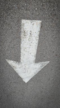 Asfalt yol yüzeyinde beyaz boyalı ok, ulaşım koşullarında yön ve navigasyonu temsil eder.