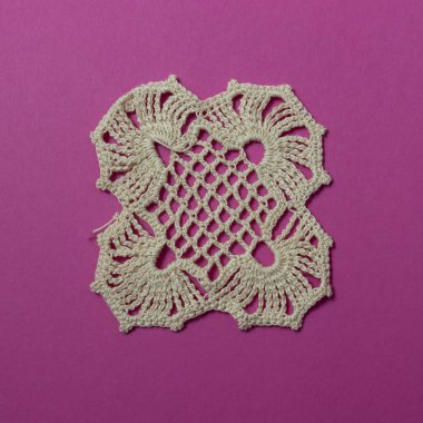 Siklamen renk arka planında bej rengi el yapımı dantel örgü..