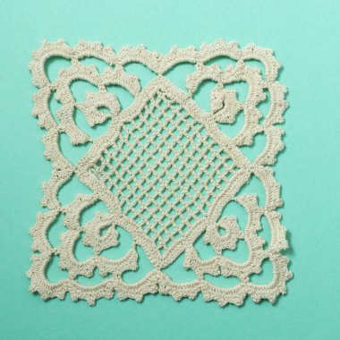 Turkuaz arka planda bej rengi el yapımı dantel örgü.