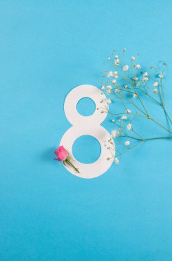 Number 8 with fresh spring flowers with green leaves on bright white background. Minimal Women's day, March 8th or birthday concept. Flat lay, top view.