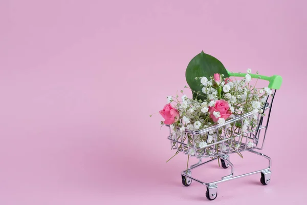 Cart of gypsophilas flowers and roses on pink background woman's day concept