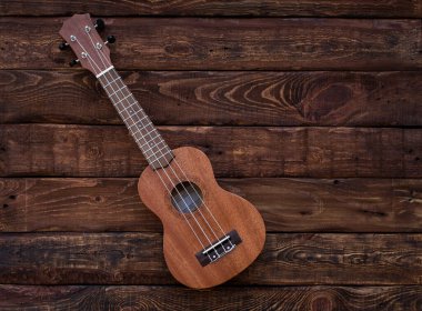 Ukulele gitarı ahşap arka planda izole edilmiş. Mesaj için yer var. Müzik arkaplanı