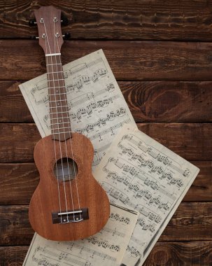 Ukulele gitarı ahşap arka planda notalar üzerinde