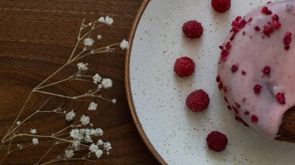 sweet bakery on white plate with raspberry close up on wooden plate with flowers decoration