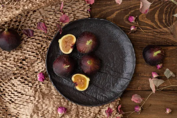 Fresh Fig fruit on black plate on wooden background. Beautiful Violet Fruit Close Up.