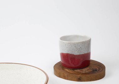 Küçük seramik mor ve beyaz bardak ahşap parçanın üzerinde, yakın plan, beyaz arkaplan