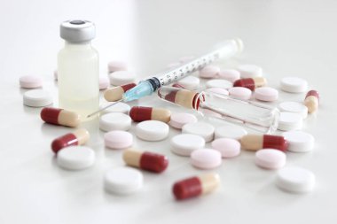 Beyaz arka planda 1 ml uyuşturucu, iğne, ilaç tableti ve kapsül içeren plastik şırınga
