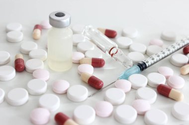 Beyaz arka planda 1 ml uyuşturucu, iğne, ilaç tableti ve kapsül içeren plastik şırınga