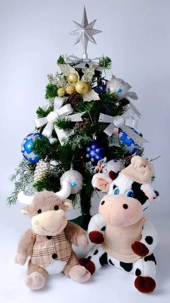 Soft toys - a cow and a bull under a decorated Christmas tree