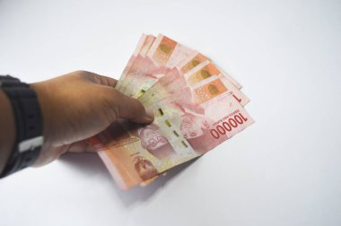 Beyaz arka planda izole edilmiş nakit ödeme konsepti. Bir iş adamının eli 100.000 rupilik banknotları tutuyor.