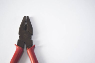 Beyaz arkaplanda kırmızı ve siyah renkte pense