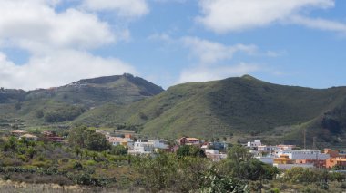Tuhaf bir köy, yemyeşil, sakin bir dağ manzarası.