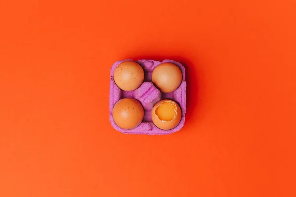 Vier Kippeneieren Paars Eierdoosje Oranje Achtergrond Bovenaanzicht Stockfoto