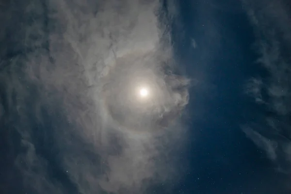 A lunar halo around the moon, showing multiple bands of color in its rainbow halo form. High quality photo