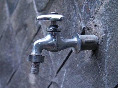 Su musluğu, arka planda taş duvar olan musluk