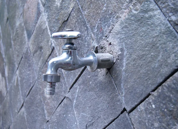 stock image water tap, faucet with stone wall background