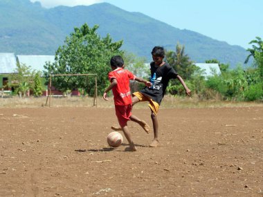 Maumere, Flores, Endonezya - 23 Mayıs 2023: Asyalı çocuklar sahada futbol oynuyorlar.