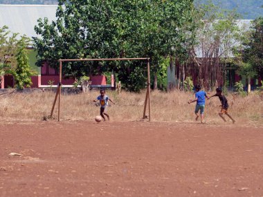 Maumere, Flores, Endonezya - 23 Mayıs 2023: Asyalı çocuklar sahada futbol oynuyorlar.