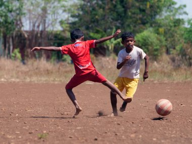 Maumere, Flores, Endonezya - 23 Mayıs 2023: Asyalı çocuklar sahada futbol oynuyorlar.