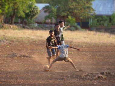 Maumere, Flores, Endonezya - 23 Mayıs 2023: Asyalı çocuklar sahada futbol oynuyorlar.