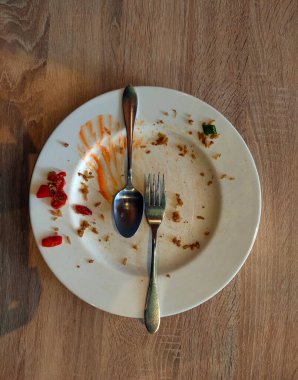 Üzerinde çatal ve kaşık olan kullanılmış bir yemek tabağının üst görüntüsü. Yemek için resim
