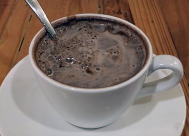 Tahta bir masada bir fincan sıcak çikolata.