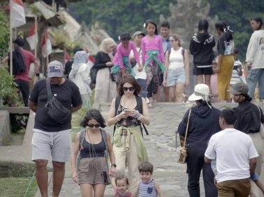 Bali, Indonesia - August 17, 2024: crowds of tourists visit panglipuran village which is the cleanest village in the world.  clipart