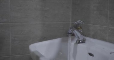 Lavabo musluğunu açan bir adamın elini kapat..