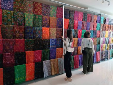 20 Kasım 2024 'te Bali, Endonezya' da bir batik dükkanında iki Asyalı kız Balili batik kumaşa bakıyor..