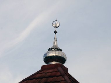 Bulutlu gökyüzünün altında parlak bir cami kubbesi.