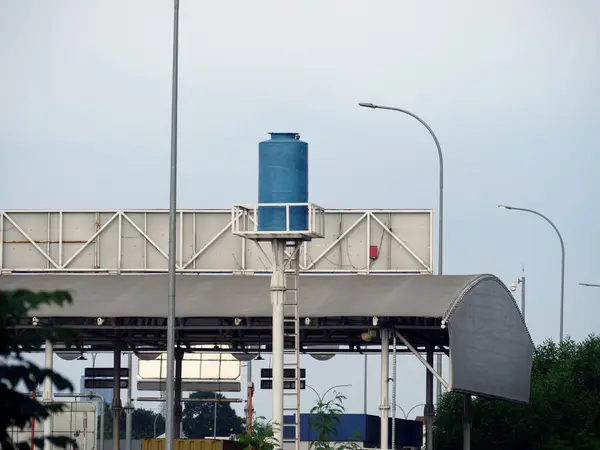 Metal bir yapının üzerinde yükseltilmiş mavi su tankı