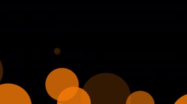 Soyut büyük parlak turuncu bokeh parçacıkları siyah arkaplanda yüzer..
